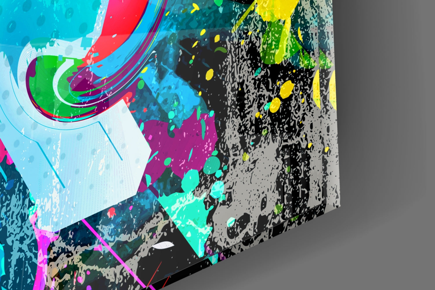 Angled perspective view of colorful abstract Ebruli glass wall art with vibrant splashes of cyan, magenta, yellow, and lime green on black and gray textured background.