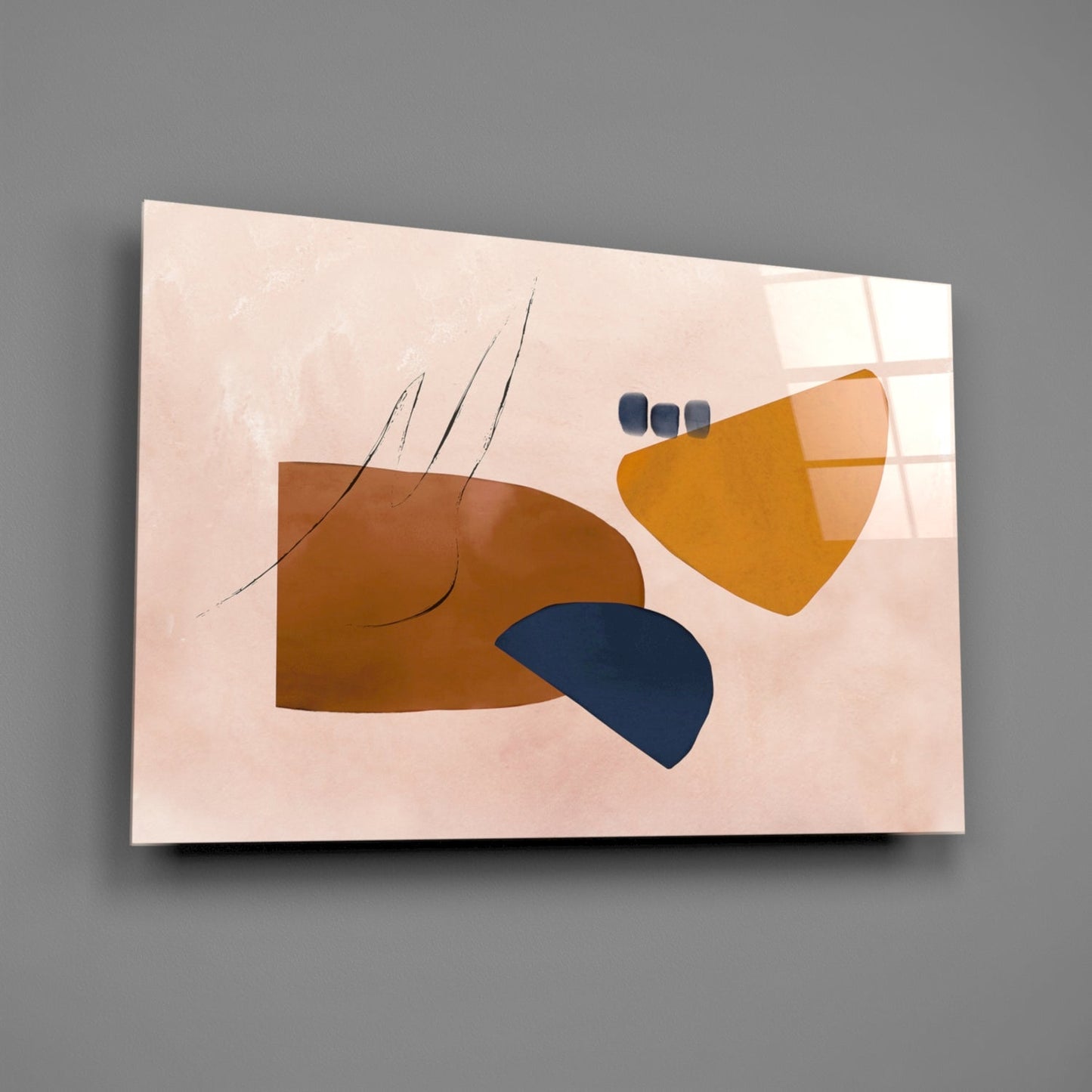 Abstract brown glass wall art featuring geometric shapes in brown, gold, and navy blue on a pale pink background, displayed at an angle against a gray wall.