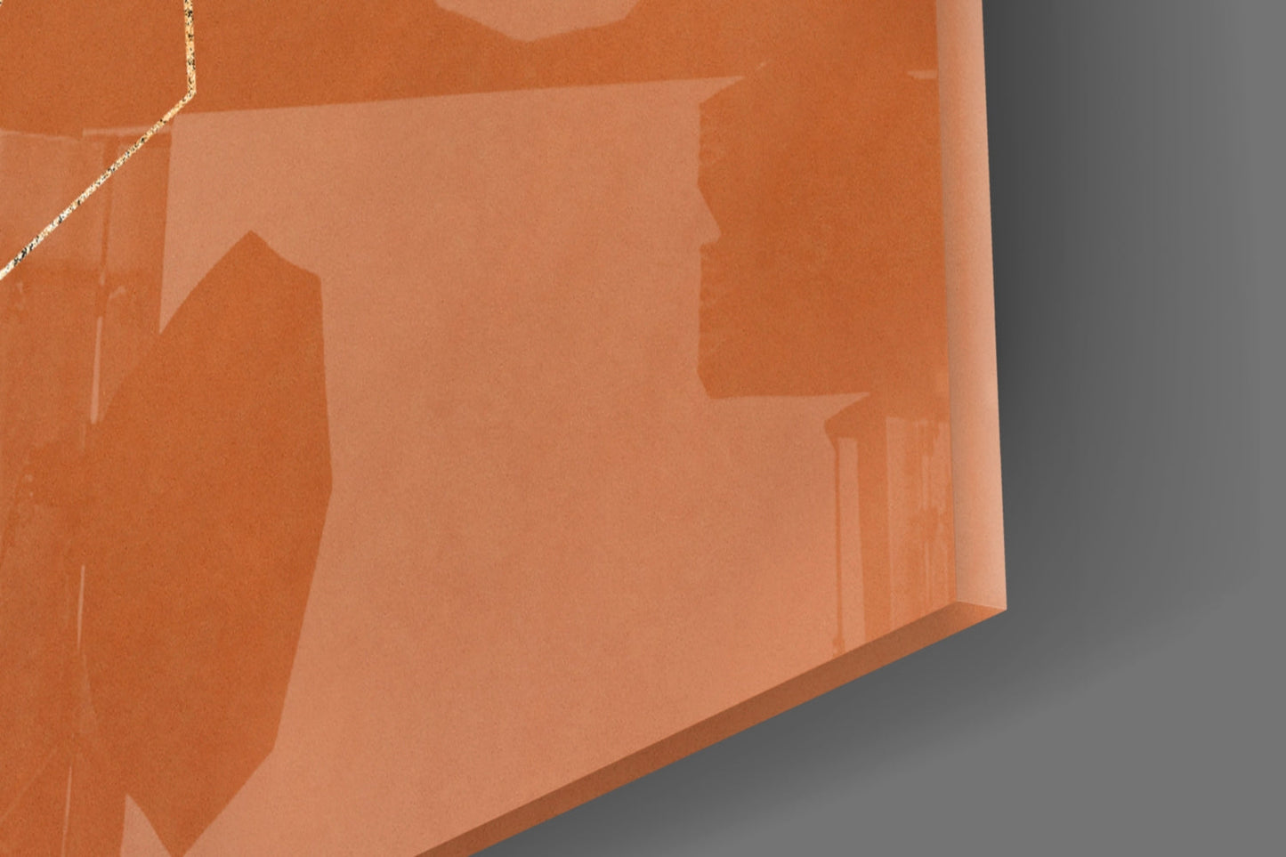 Close-up angled view of cinnamon-toned glass wall art showing layered geometric shapes with metallic gold accent line against gray background.
