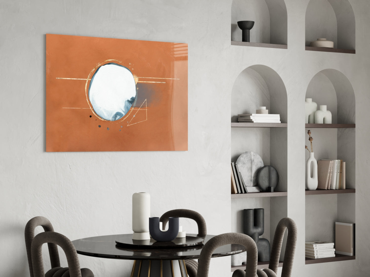 Abstract Cinnamon Glass Wall Art with circular mirror and geometric line details displayed above black round dining table with gray chairs.
