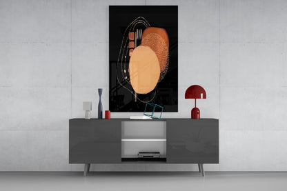Abstract black glass wall art with orange and terracotta circular shapes and gold line details displayed above gray media console.
