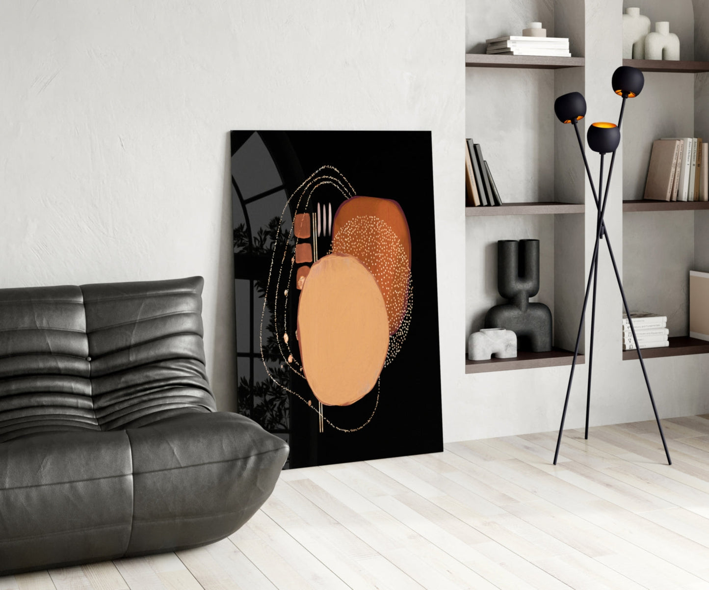 Abstract black glass wall art with terracotta and gold circular design displayed in modern living room with gray sofa and shelving.