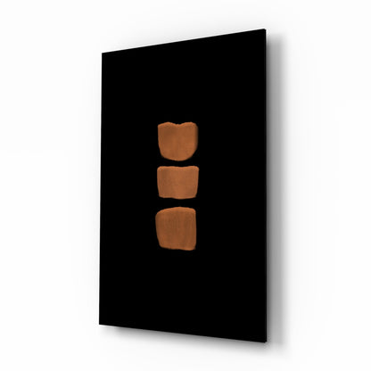 Black glass panel with three stacked terracotta-colored rounded square shapes arranged vertically in center, photographed at angled perspective.