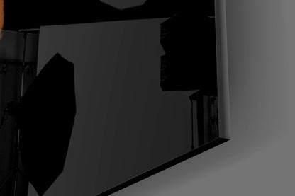 Close-up angled view of abstract column glass wall art with dark silhouettes against gray background, showing geometric shapes and reflective surfaces.