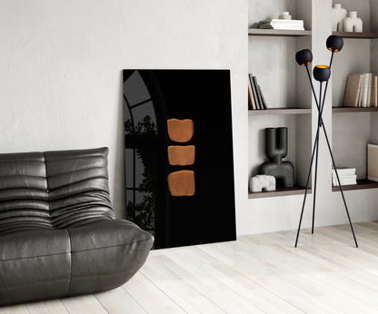 Modern living room interior featuring black glass wall art with three orange rounded square shapes displayed against white shelving and gray leather furniture.