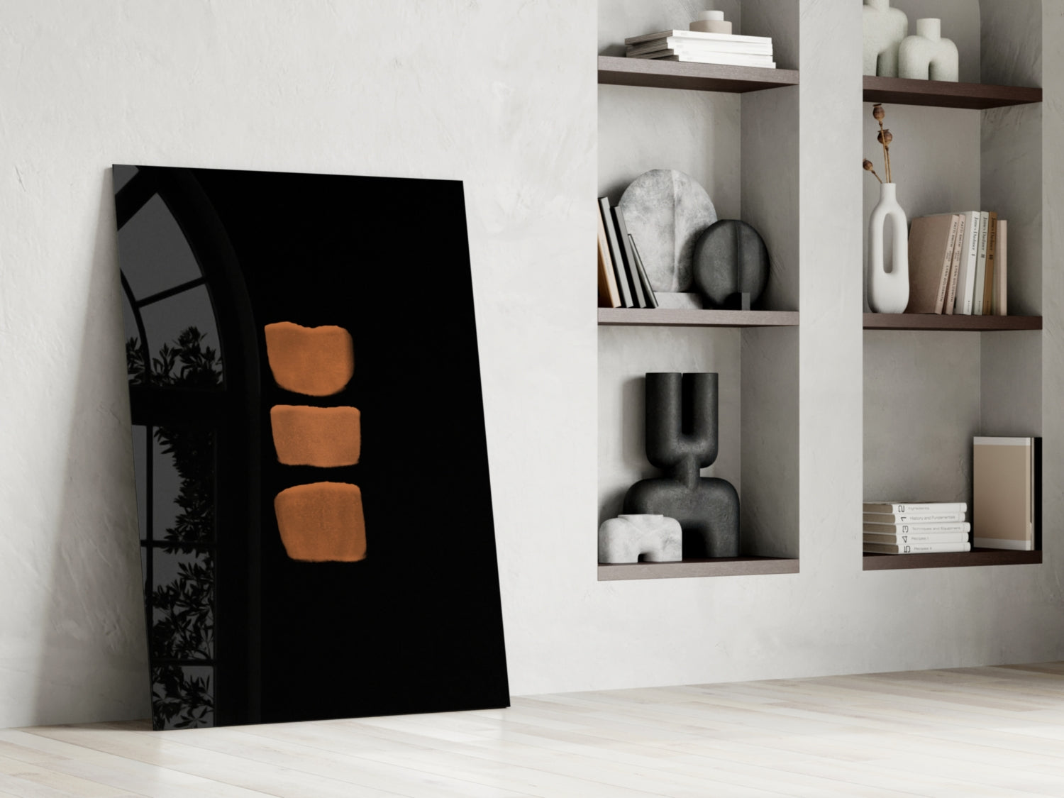 Black glass wall art with three orange squares displayed leaning against white wall beside floating shelves with decorative objects.