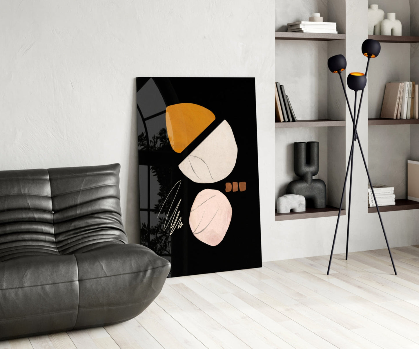 Modern living room with black glass wall art featuring orange and cream acorn design displayed next to gray leather sofa.