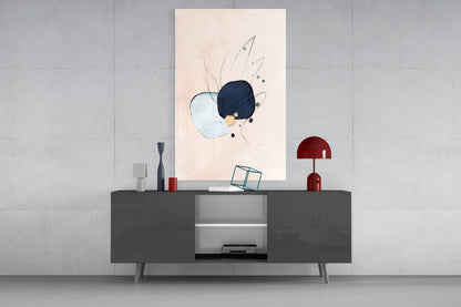 Abstract hand glass wall art with light blue and dark navy circles and line details displayed above gray sideboard with red lamp and decorative objects.