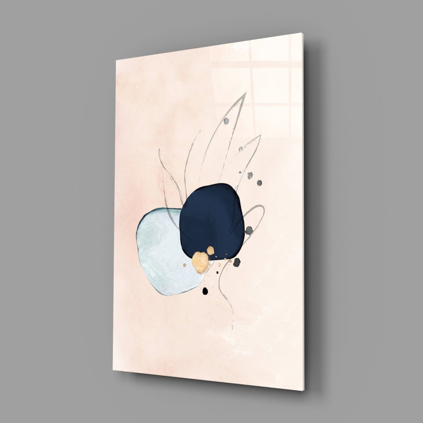Angled view of glass wall art displaying abstract shapes in light blue, dark navy, gold, and black on cream background, mounted on gray wall.