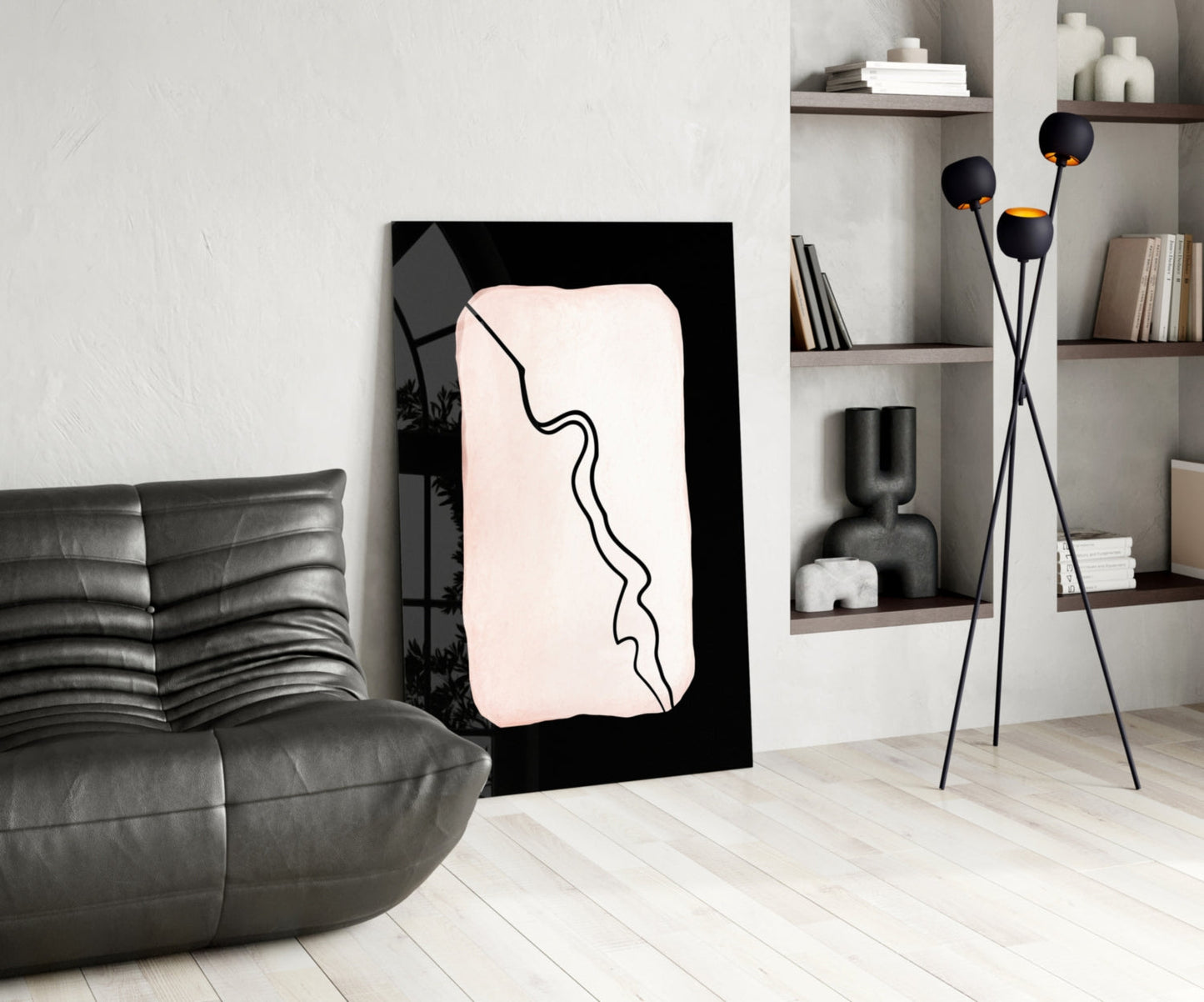 Modern living room interior featuring a black-framed glass wall art with cream background and continuous black line design, displayed between gray leather sofa and white shelving unit.
