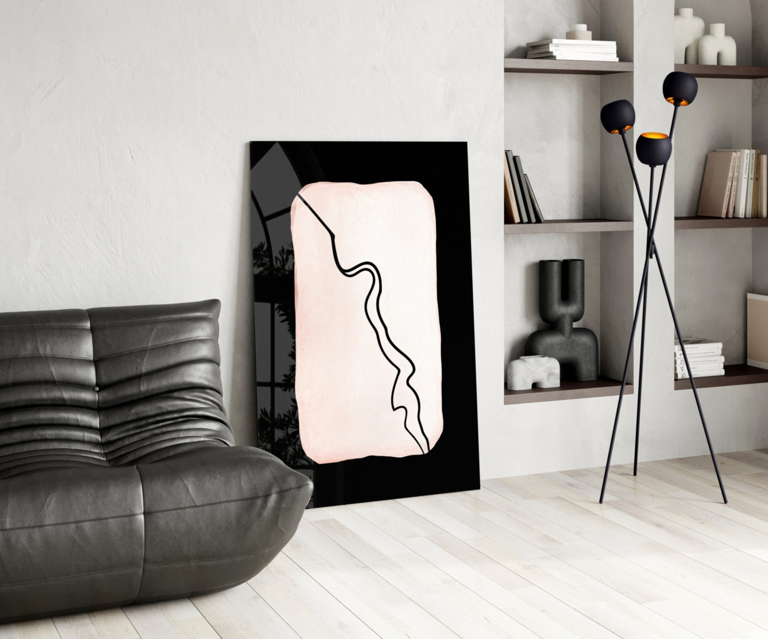 Modern living room interior featuring a black-framed glass wall art with cream background and continuous black line design, displayed between gray leather sofa and white shelving unit.