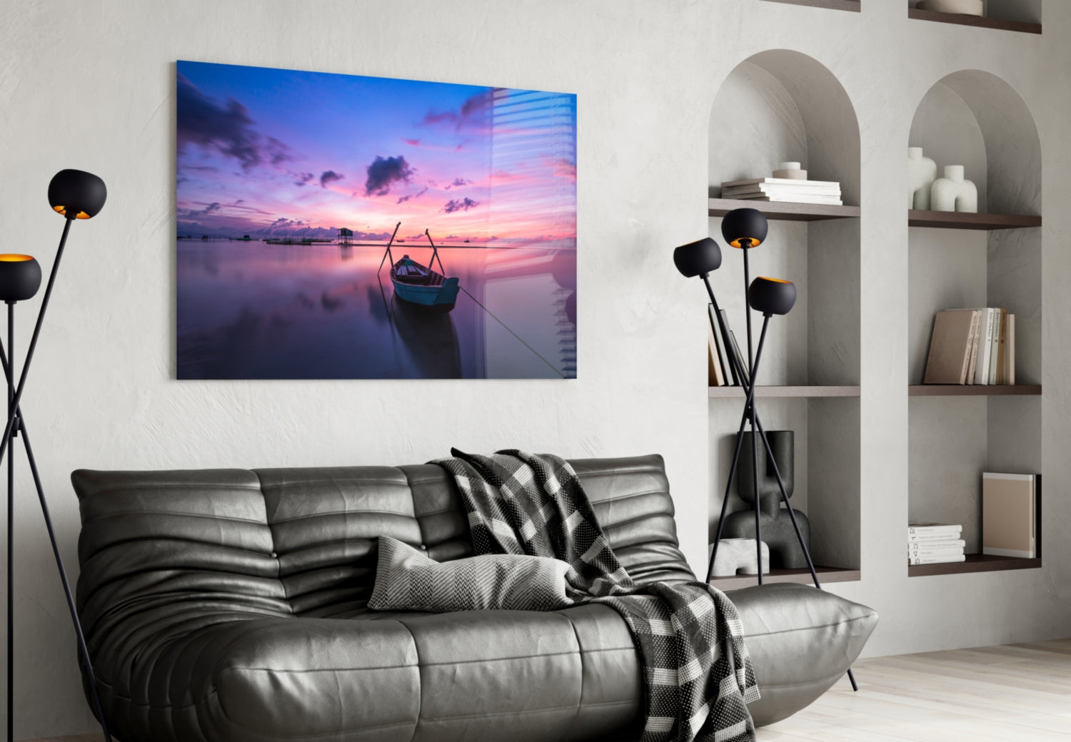 Glass wall art depicting a purple and pink sunset over calm water with a moored boat, displayed above a gray sofa in a modern living room.
