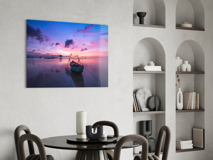 Glass wall art print of a sunset boat scene displayed above a round dining table in a modern interior setting.