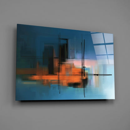 Blue and orange abstract glass wall art with black linear marks, displayed at an angle against a gray wall.