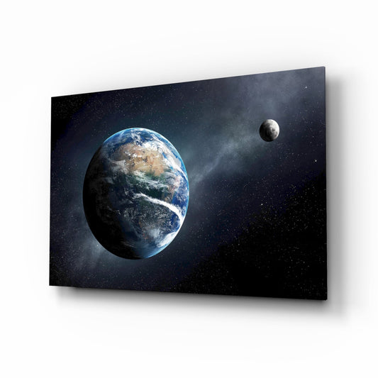 Angled perspective of glass wall art panel displaying Earth and Moon against starry black space, mounted on white background.