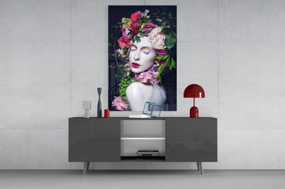 Modern living room display featuring colorful floral and woman glass wall art mounted above gray media console with red lamp and decorative accessories.