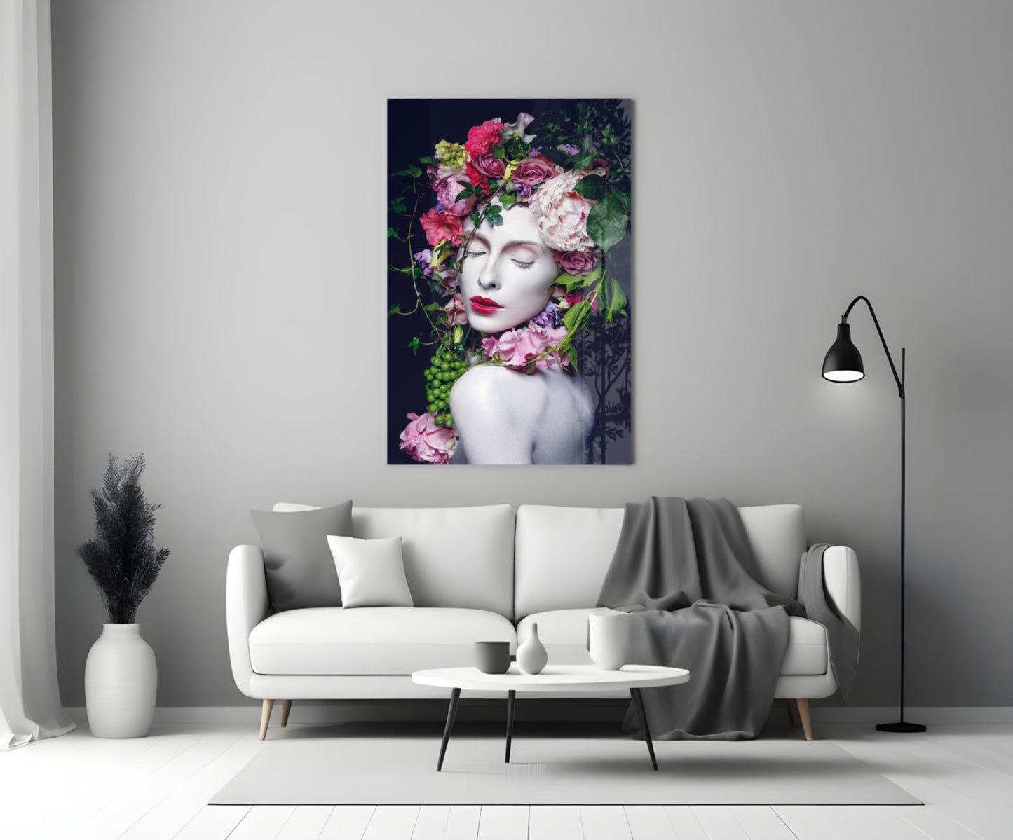 Glass wall art depicting a woman's face with vibrant pink and white flowers adorning her head and shoulders against dark background, displayed above white sofa in modern living room.