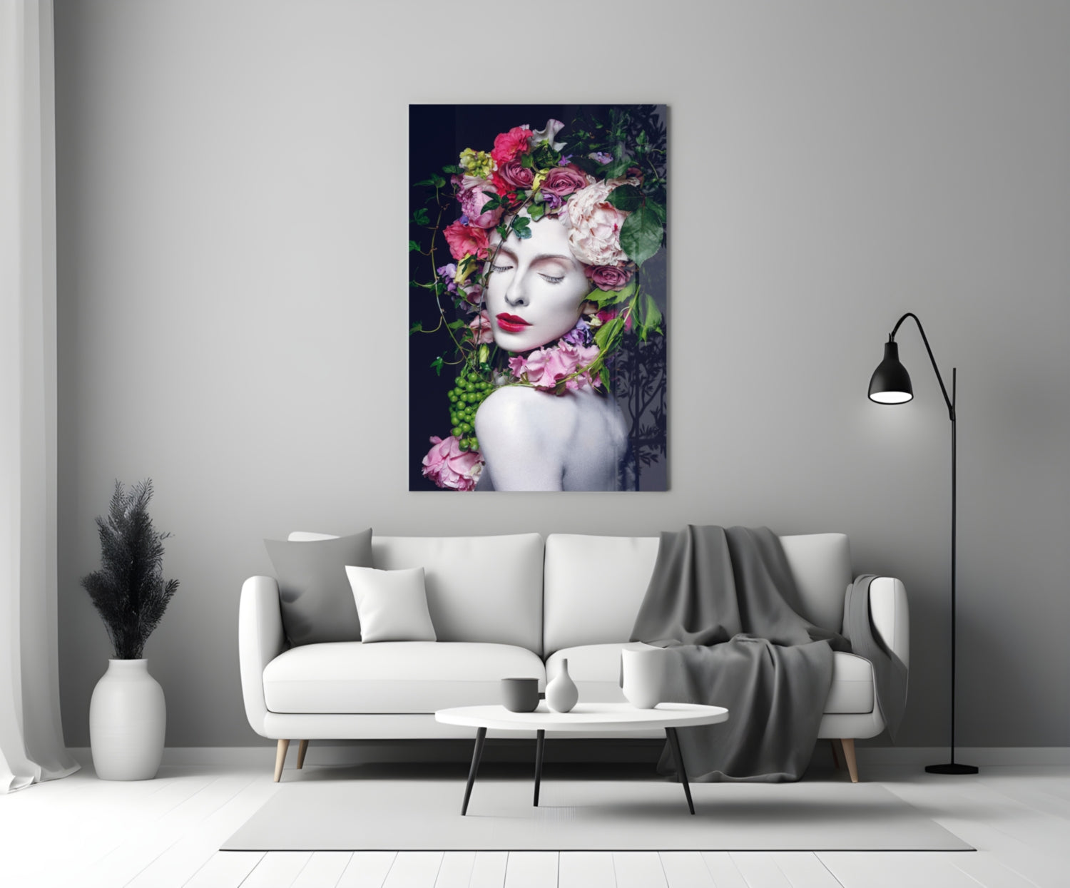 Glass wall art depicting a woman's face with vibrant pink and white flowers adorning her head and shoulders against dark background, displayed above white sofa in modern living room.