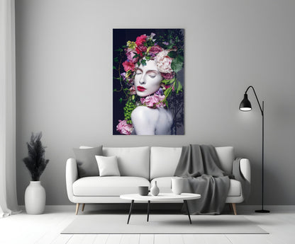 Glass wall art depicting a woman's face with vibrant pink and white flowers adorning her head and shoulders against dark background, displayed above white sofa in modern living room.