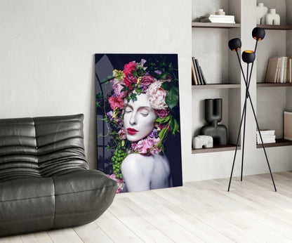 Modern living room with glass wall art depicting a woman's face surrounded by pink and purple flowers against dark background, displayed next to gray sofa.