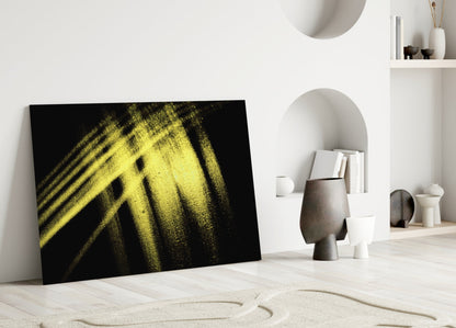 Yellow and black abstract glass artwork leaning against white wall in minimalist interior setting.