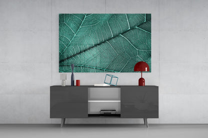 Green leaf texture glass art hanging above dark gray media console with red decorative objects and white shelving.