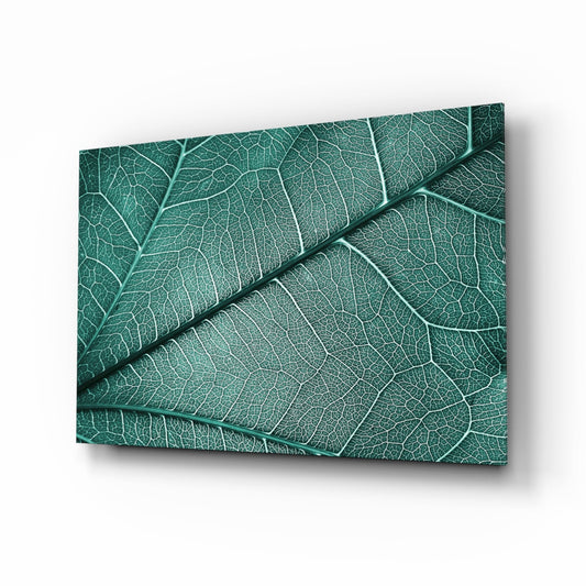 Angled perspective of teal glass wall art displaying detailed leaf vein patterns with shadow depth effect.