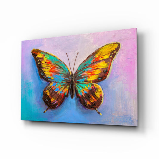 Colorful butterfly with yellow, orange, teal, and brown wings displayed on glass against a gradient pink and blue painted background.