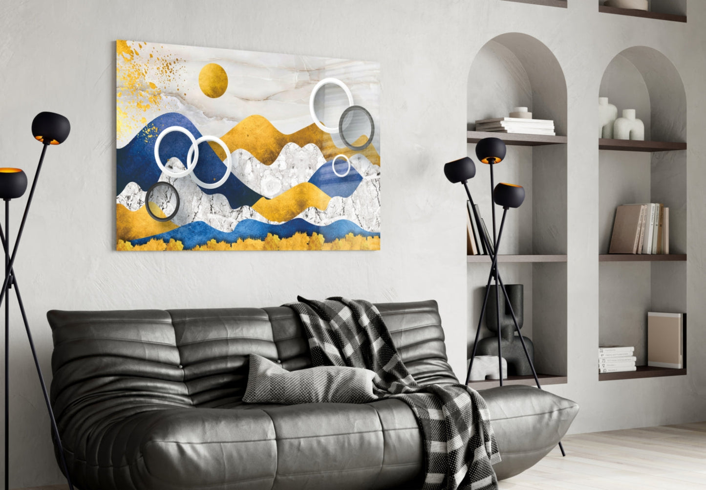 Modern living room featuring abstract glass wall art with blue, gold, and white layered mountains above a black leather sofa.