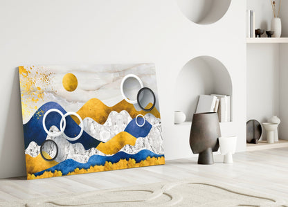 Colorful Mountains Glass Wall Art leaning against white wall in minimalist room setting with decorative objects and shelving.