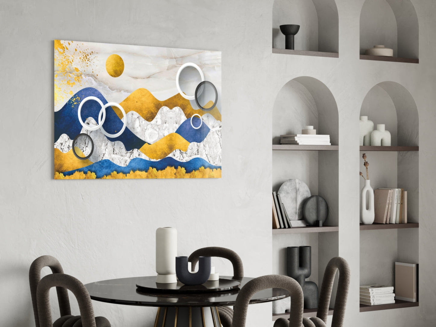 Colorful Mountains Glass Wall Art displayed above a round black dining table with gray chairs in a modern room with white built-in shelving.
