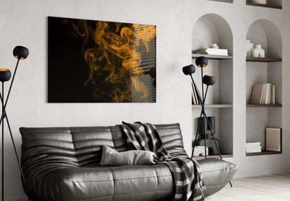 Orange smoke swirls on black glass art displayed above grey leather sofa in modern living room.