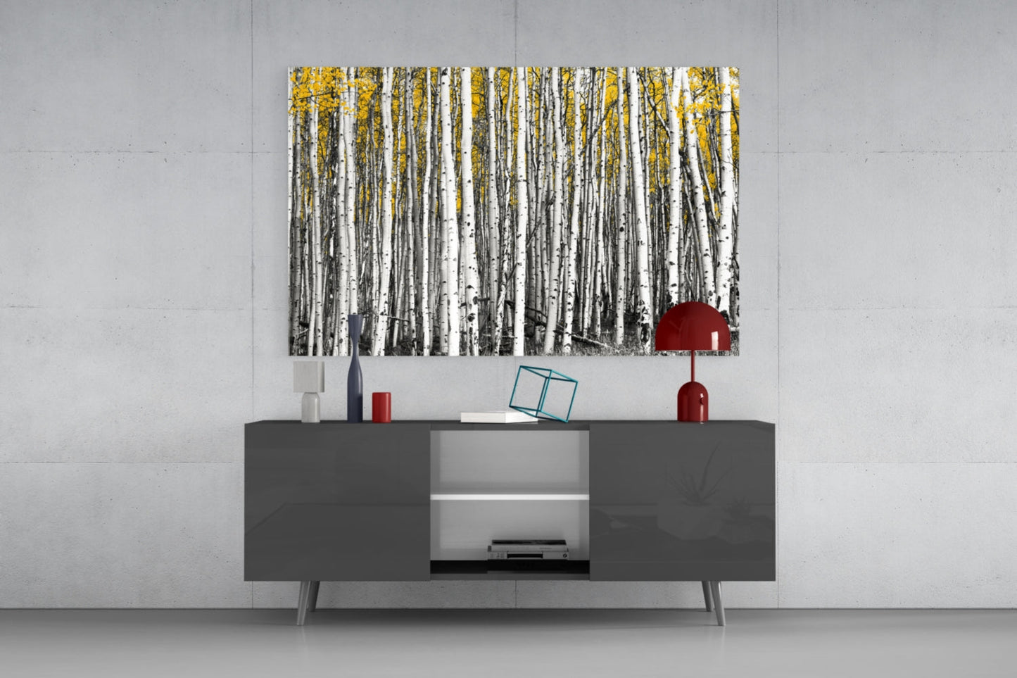 Yellow Forest Glass Wall Art displayed above a dark gray media console with red decorative accessories in a minimalist interior setting.