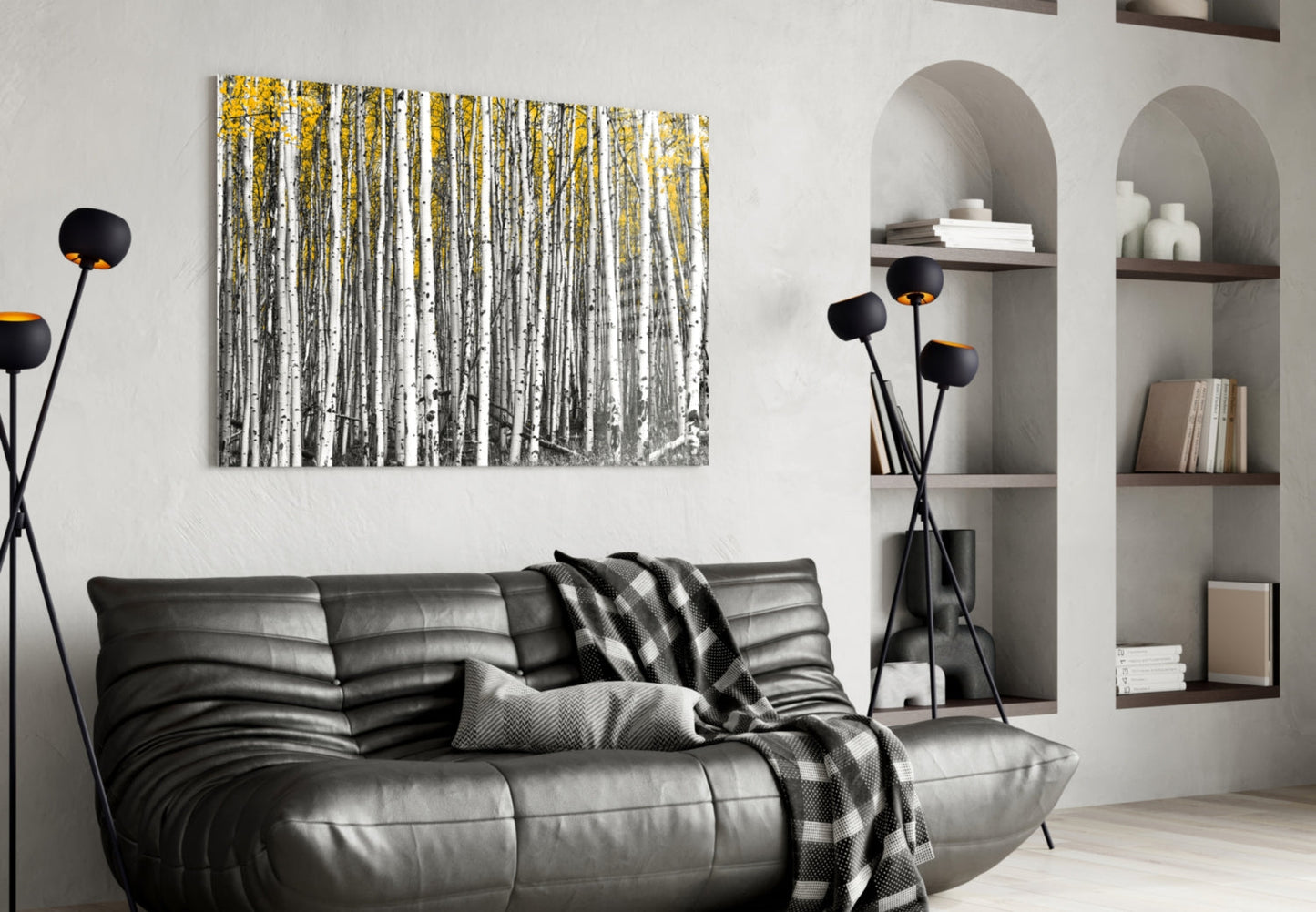 Yellow Forest glass wall art displaying birch trees with white trunks and golden foliage above a black leather sofa in a modern living room.