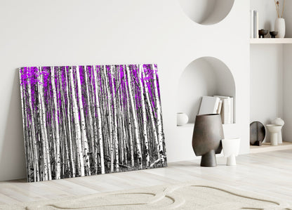 Purple and white birch forest glass wall art leaning against white wall in minimalist room setting.