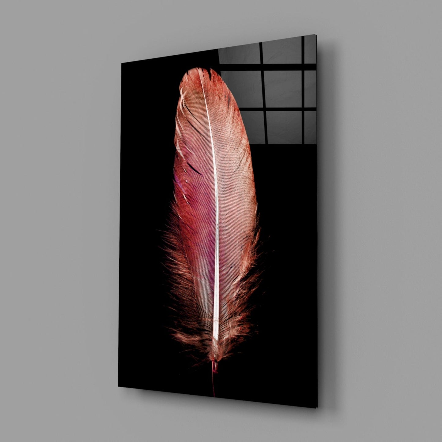 Red feather glass wall art displayed at an angle against gray background, showing black frame and grid pattern detail.