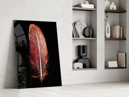Red feather glass tile leaning against white wall beside shelving with decorative objects and books.
