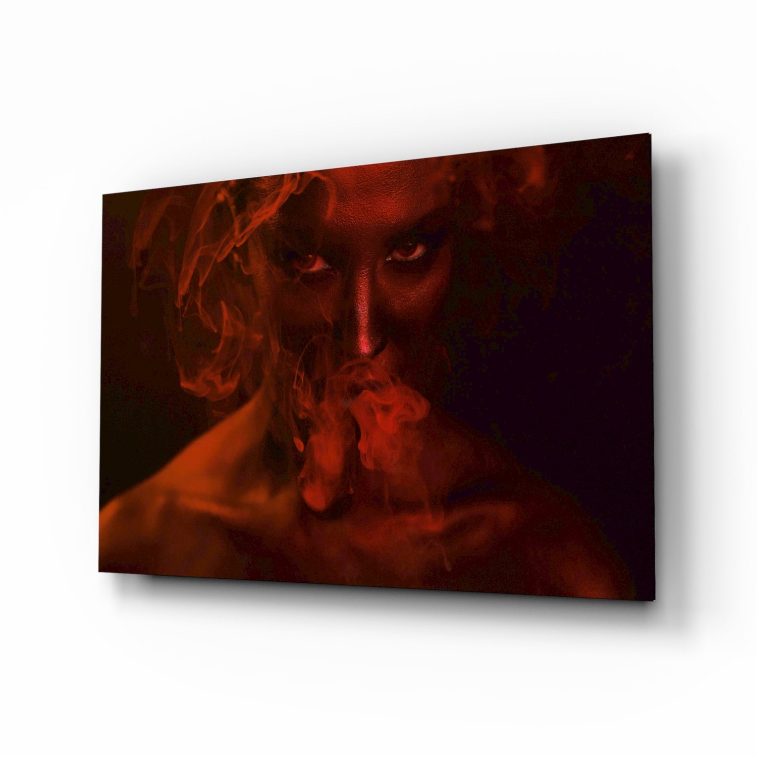 Glass wall art panel displaying a woman's face emerging from red smoke against a dark background, mounted at an angle.