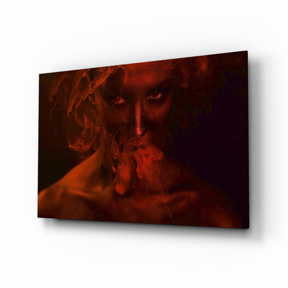 Glass wall art panel displaying a woman's face emerging from red smoke against a dark background, mounted at an angle.