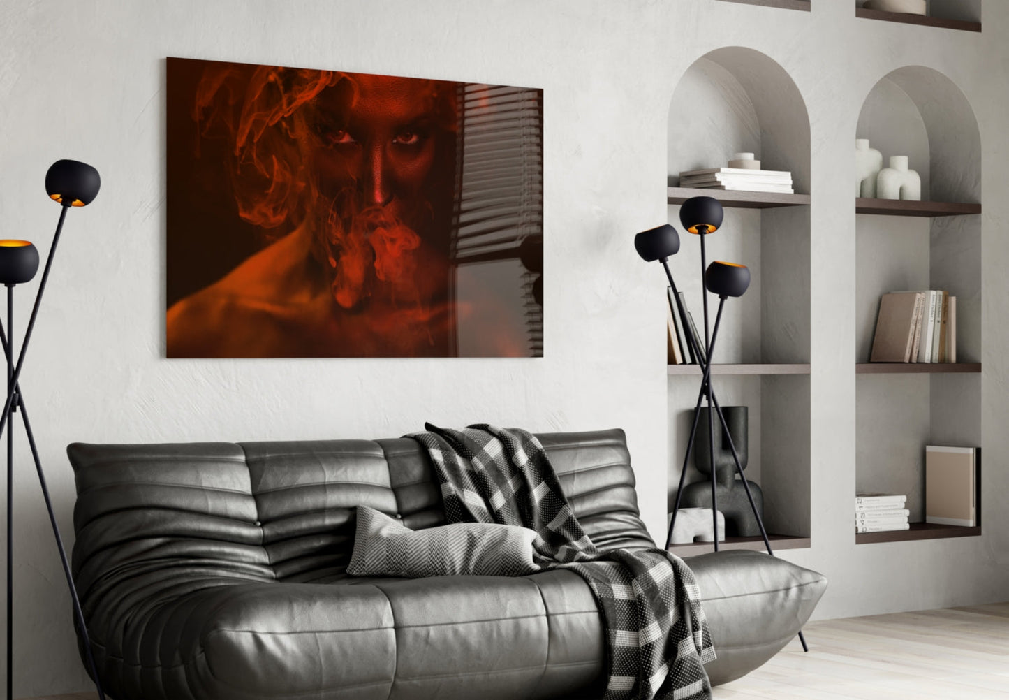 Red-toned portrait of a woman with flowing hair displayed above a black leather sofa in a modern living room interior.