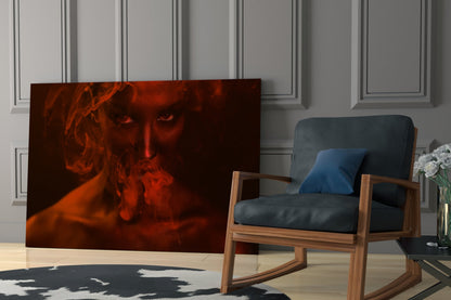Red-toned glass art panel depicting a woman's face surrounded by swirling smoke, displayed in a modern living room setting.