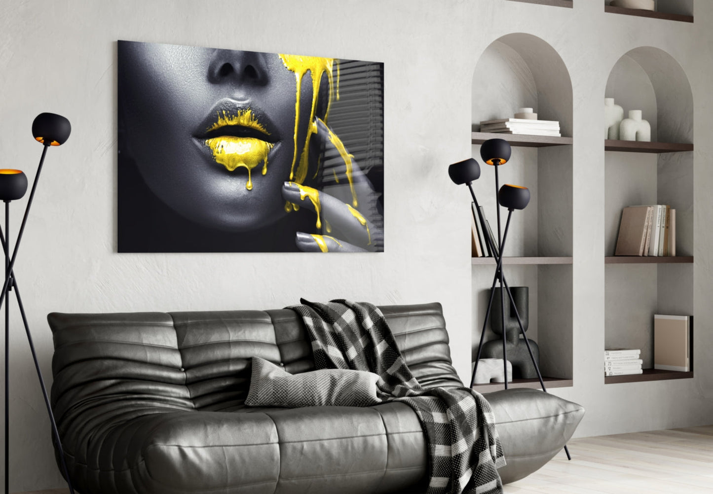 Modern living room interior with black leather sofa displaying yellow and black glass wall art of woman's face with gold dripping lips above it.