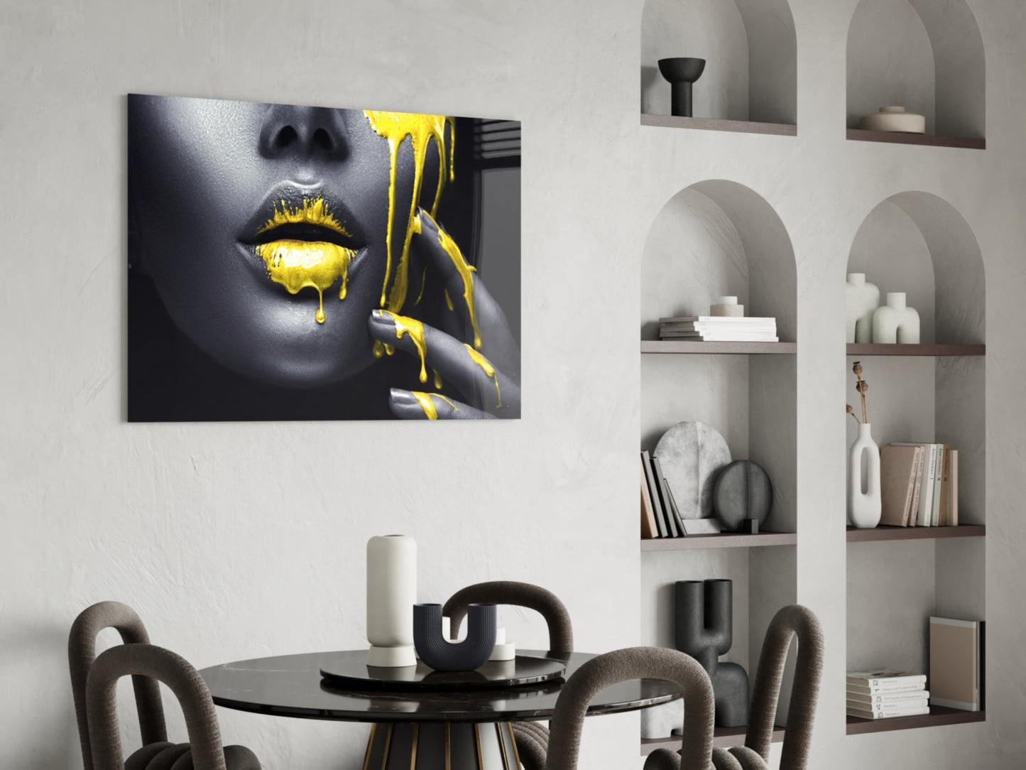 Glass wall art displaying a woman's face with gold dripping paint effect, hung above a black dining table in a modern interior.