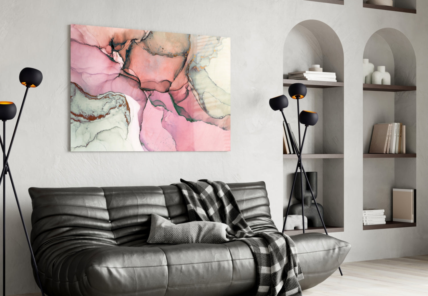 Pink marble glass wall art hung above black leather sofa in modern living room with built-in shelving.