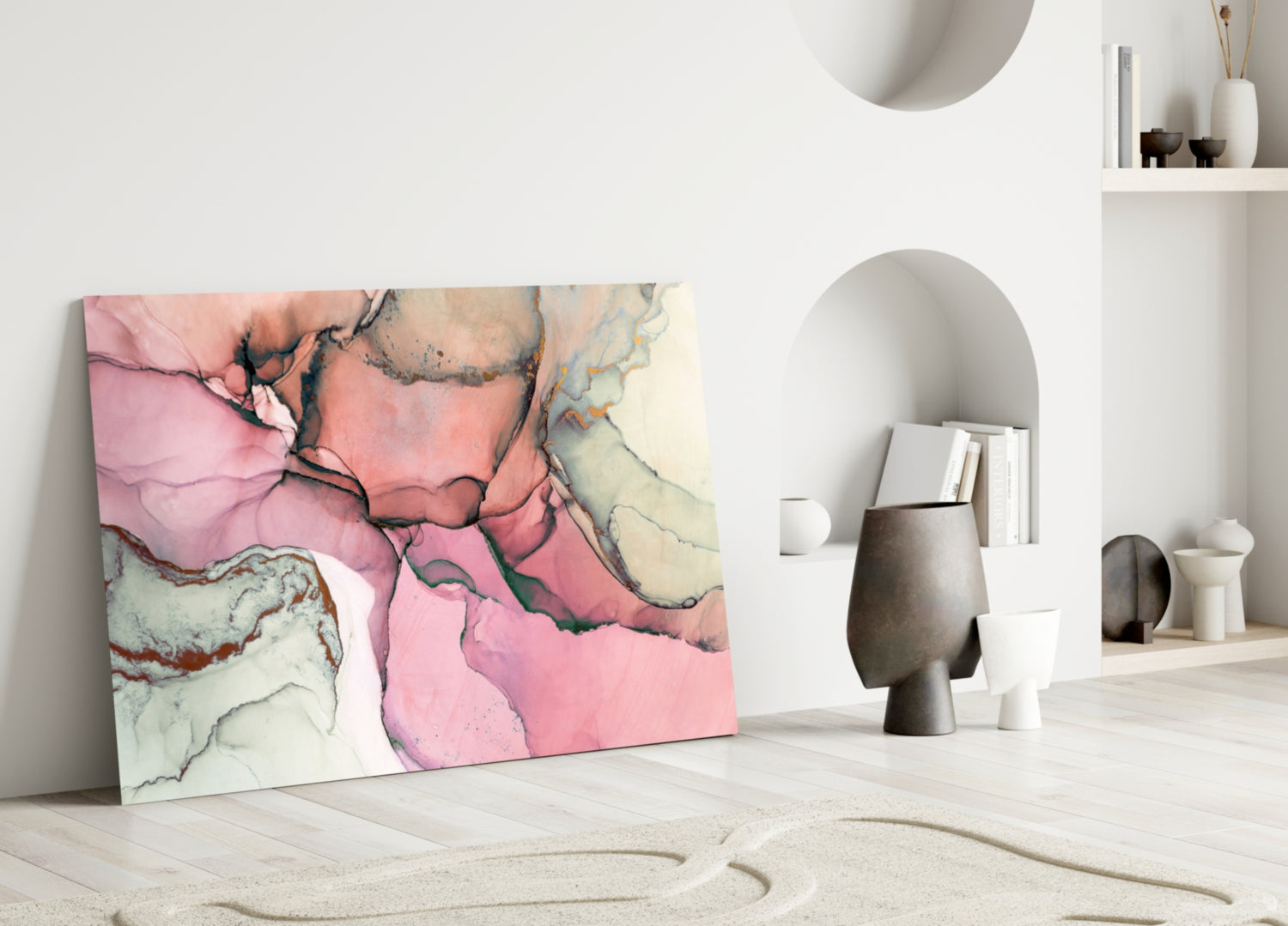 Pink marble glass wall art leaning against white wall in minimalist interior with decorative objects and shelving.