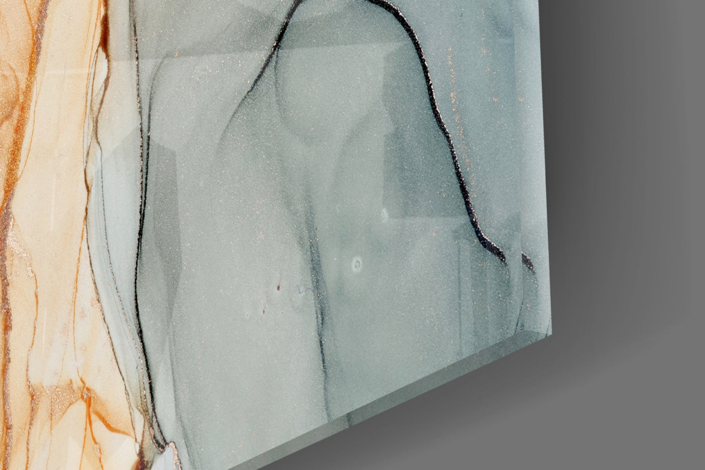 Close-up angled view of soft marble glass art showing gray-blue tones with black veining detail and peach-orange edges.