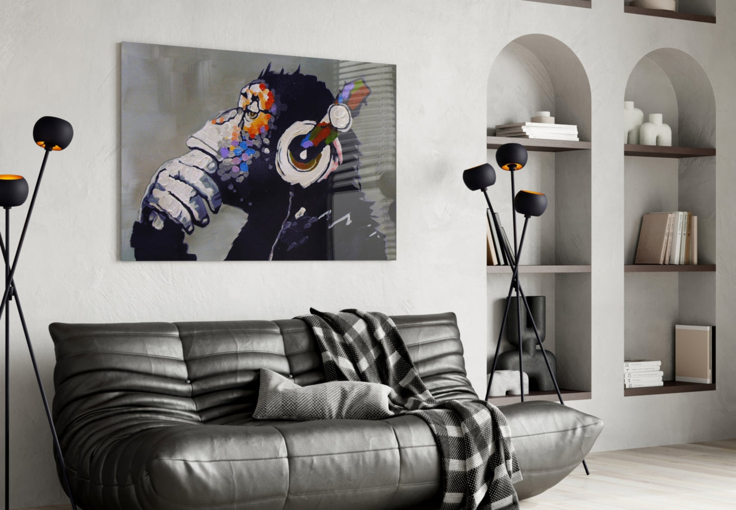 Thinking Monkey Glass Wall Art displayed above a black leather sofa in a modern living room with white shelving.