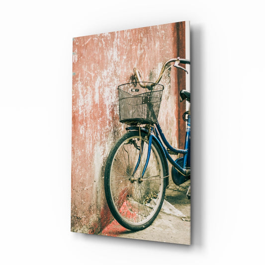 Blue vintage bicycle with wire basket leaning against weathered terracotta and white textured wall.