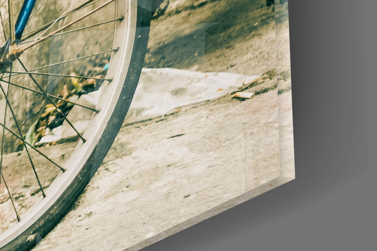 Close-up of bicycle wheel and frame against sandy beach landscape printed on glass wall art panel.