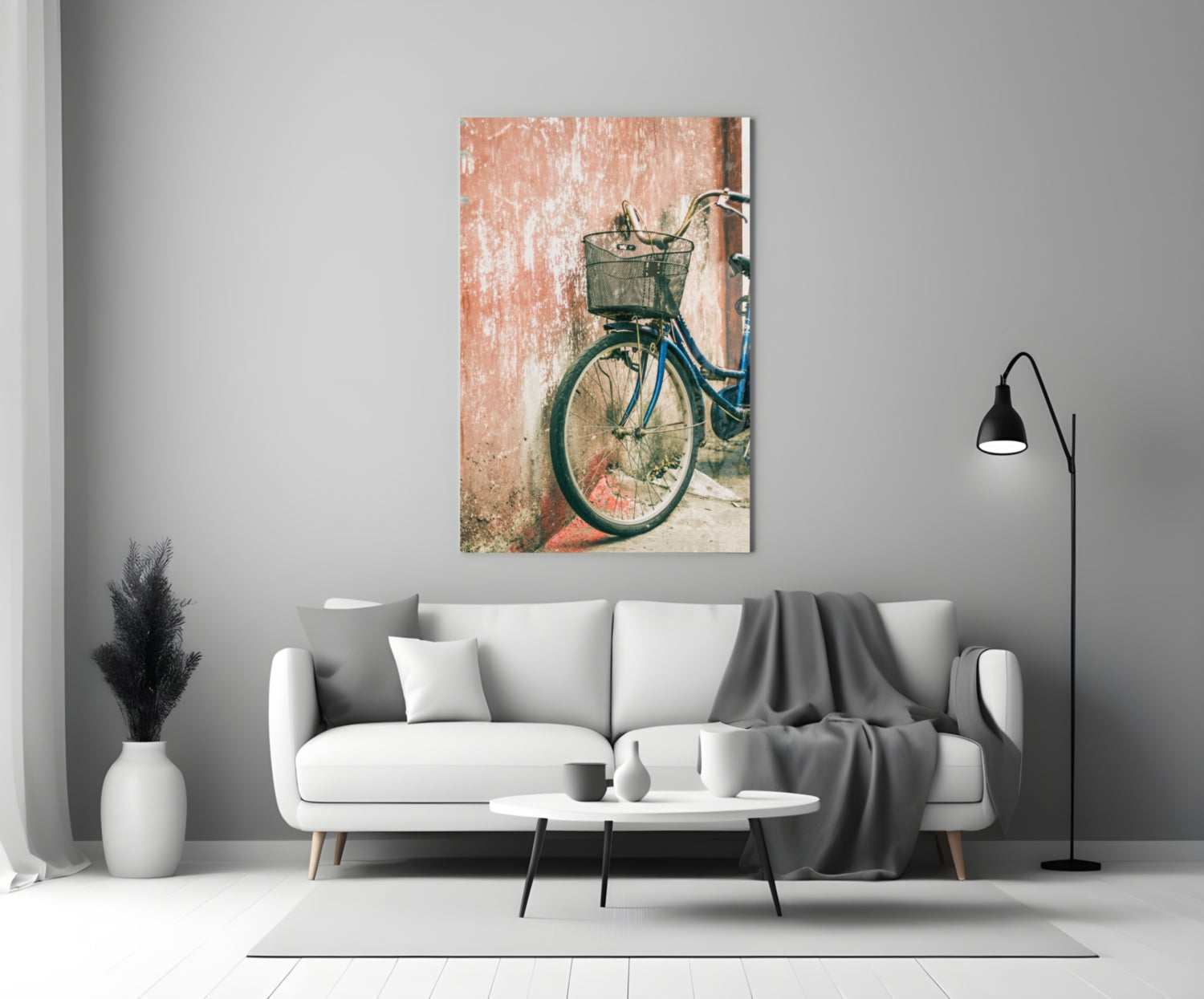 Bicycle Basket Glass Wall Art displayed above white sofa in minimalist living room with gray throw blanket and black floor lamp.